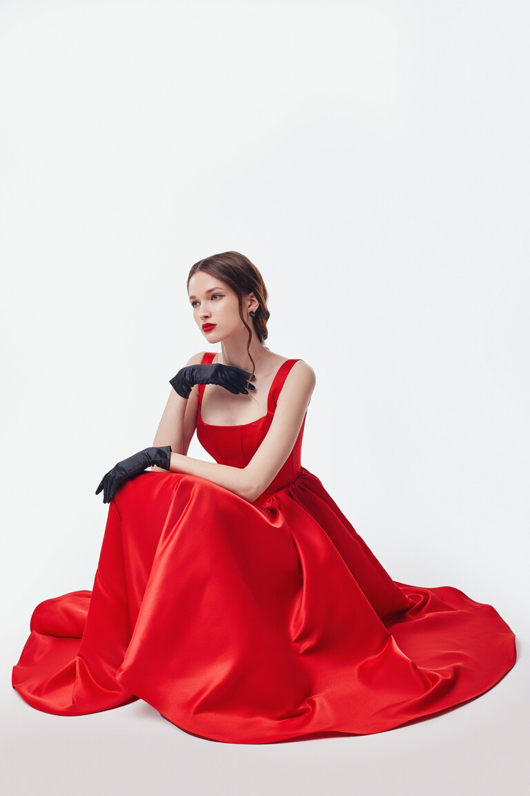 Voluminous A-Line Red Party Dress Seated view of Casia red satin party dress styled with black gloves showing voluminous skirt