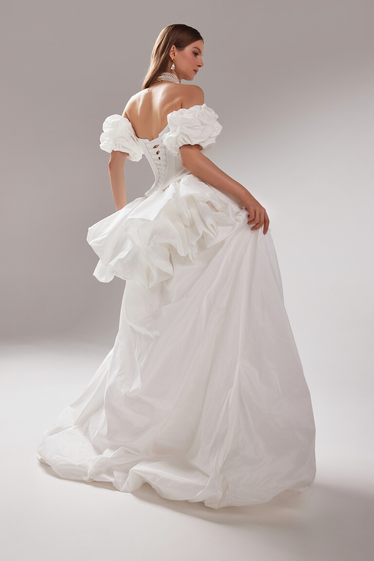 Back detail of the Amber off-white taffeta gown with its corset lacing, puff sleeves, and a draped bustle at the waist.
