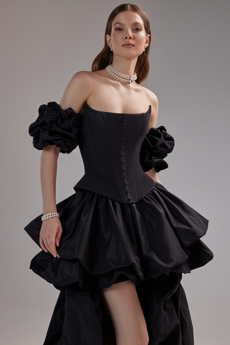 Unona Amber black evening dress three-quarter view showing the structured corset bodice and voluminous high-low bubble skirt