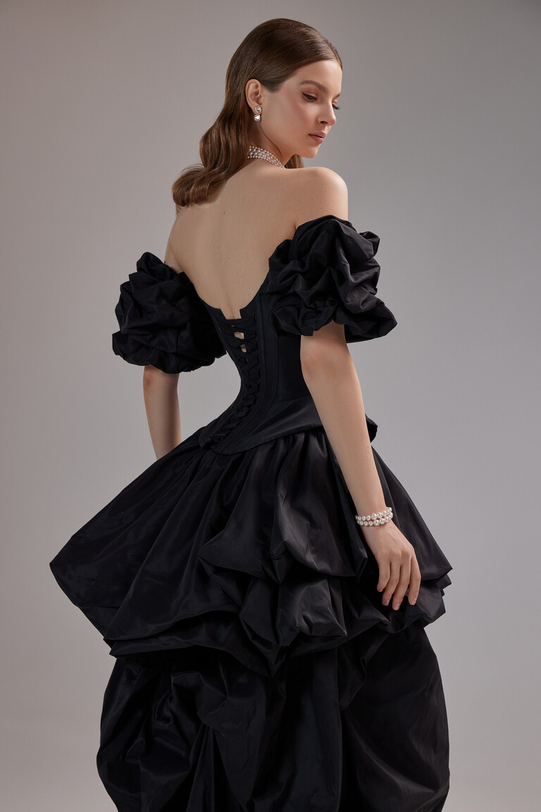 Unona Amber black gown from the side showing the elegant lace-up corset back and voluminous off-the-shoulder puff sleeves