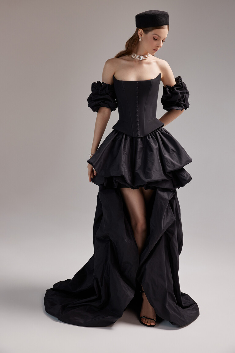 Side view of the Unona Amber black taffeta dress highlighting the sculptural high-low skirt and long elegant train