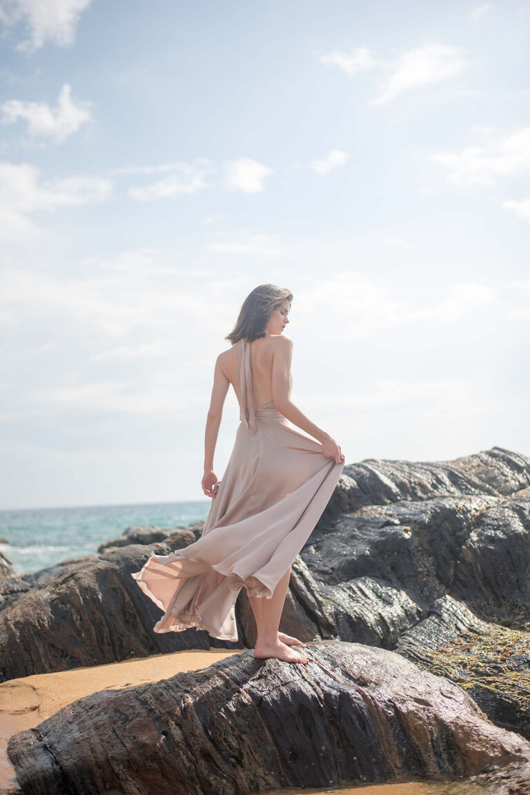 Three-quarter back view of the Unona Mary backless gown in ash silk revealing the completely open back and wide skirt.