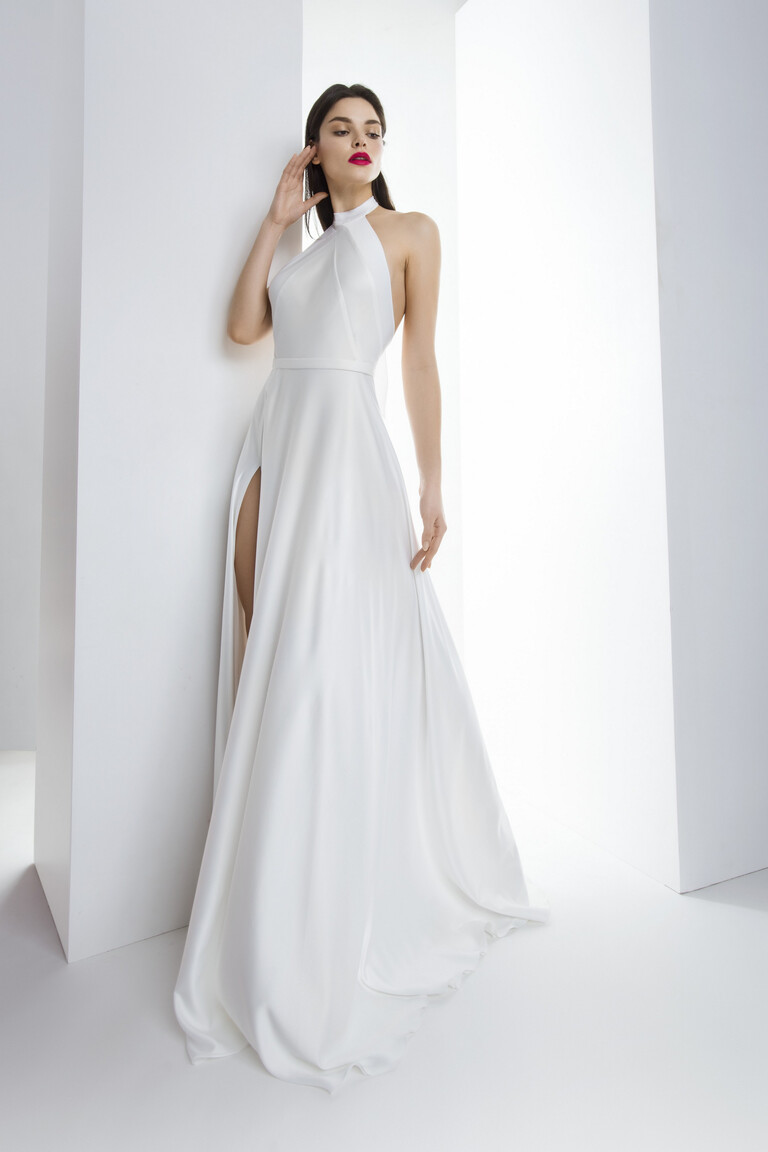 Full front view of the Unona Mary ivory silk wedding dress with a halter neck and high thigh slit in a studio