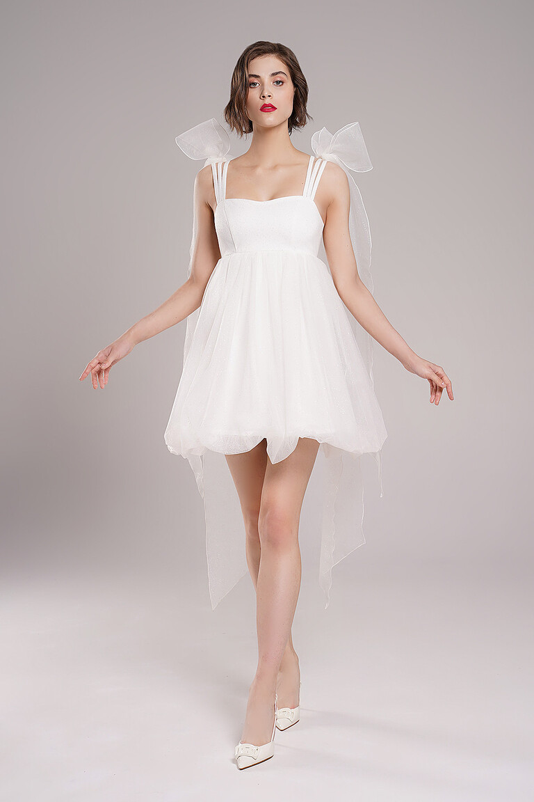 Leoni modern short ivory A-line wedding dress by Unona. Features a flattering high waistline and delicate spaghetti straps.