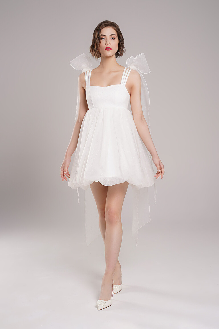 Full length view of Leoni short ivory reception dress by Unona. Shows a voluminous balloon skirt and long flowing tulle tails.