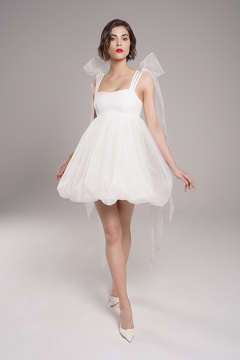 Shimmery glitter tulle details on the Leoni short ivory wedding dress by Unona. A playful babydoll design with tulle bows.
