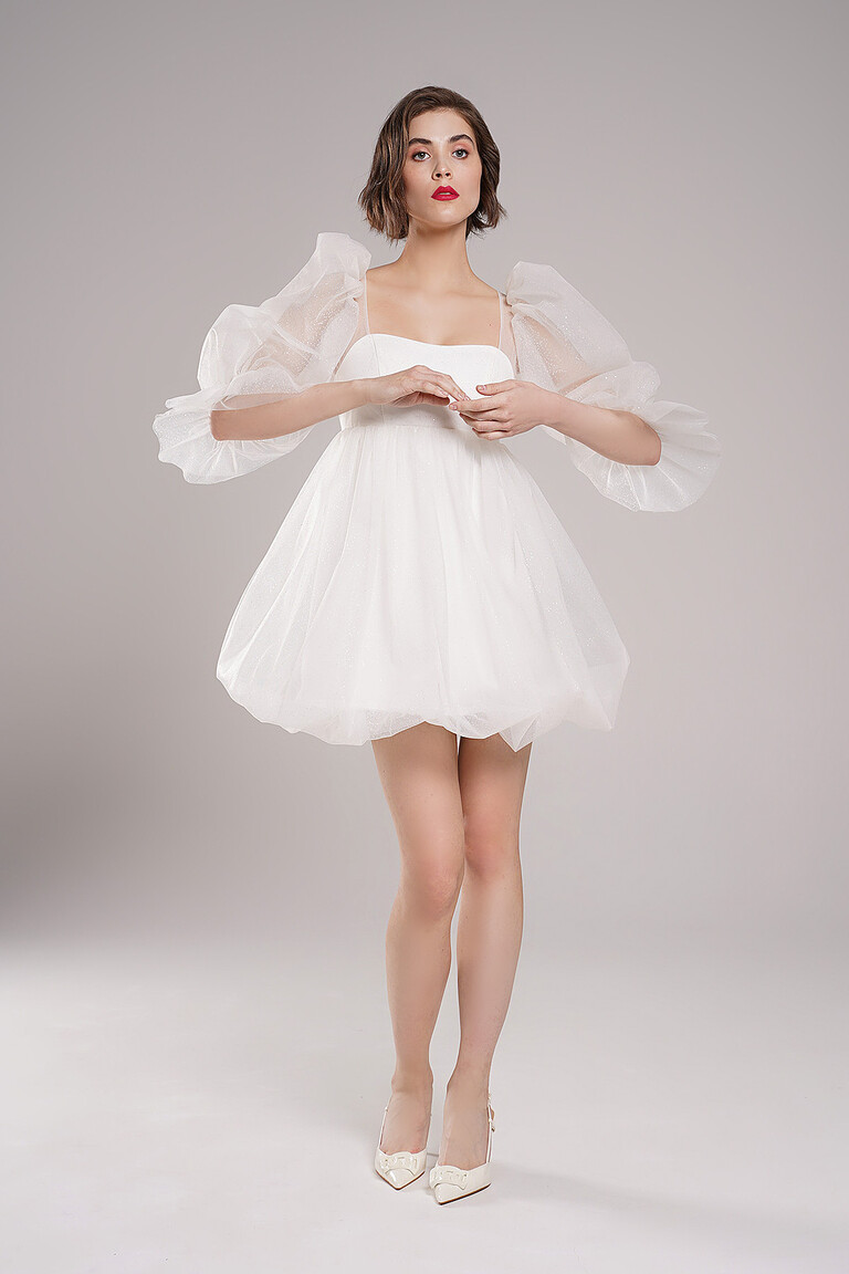 Full body view of Lessi ivory baby doll wedding dress by Unona. Showcases high waist and short glitter tulle balloon skirt.
