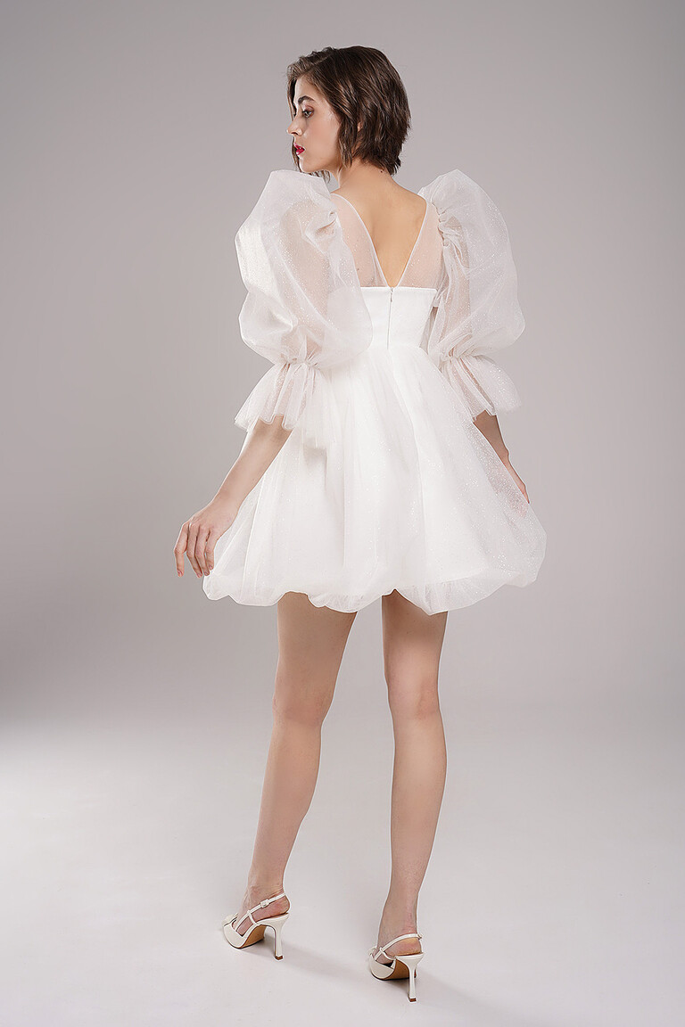 Back view of Unona Lessi short bridal dress in ivory. Shows V-shaped back detail, glitter tulle skirt and puff sleeves.