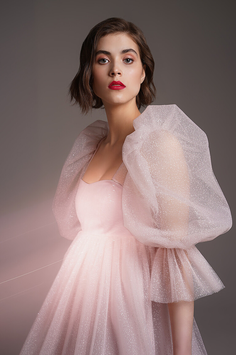 Front angle of the Lessi powder short dress. Highlights the fitted bodice, satin base, and glitter tulle puff sleeves.