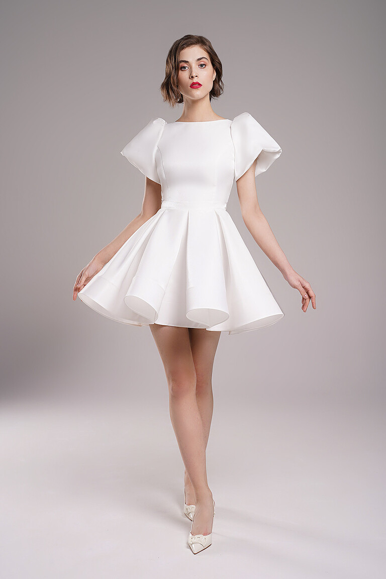 Full length front view of Audrey mini short ivory wedding dress by Unona. Features voluminous sleeves and flared skirt.