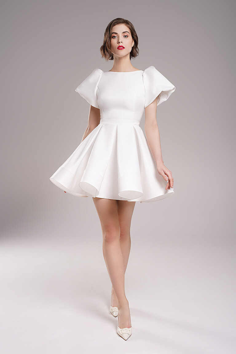 Front angle view of minimalist Audrey mini ivory bridal gown by Unona. Short lurex satin dress with bell shaped skirt.