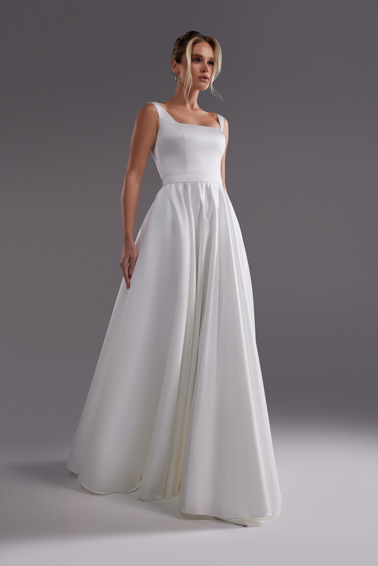 Front view of the minimalist Vlada off-white satin bridal gown featuring a square neckline and full A-line skirt