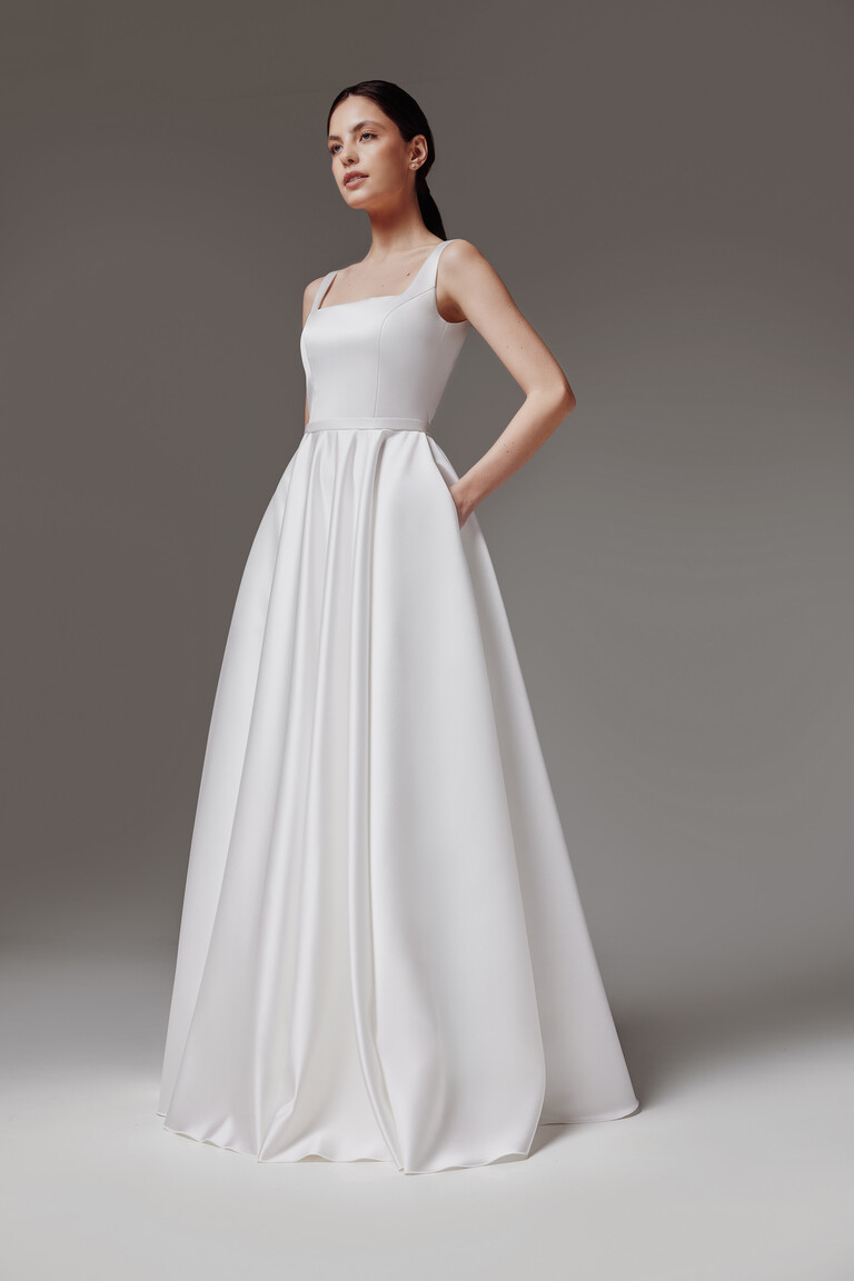 Three-quarter view of Vlada off-white A-line wedding dress with a square neckline and functional hidden pockets