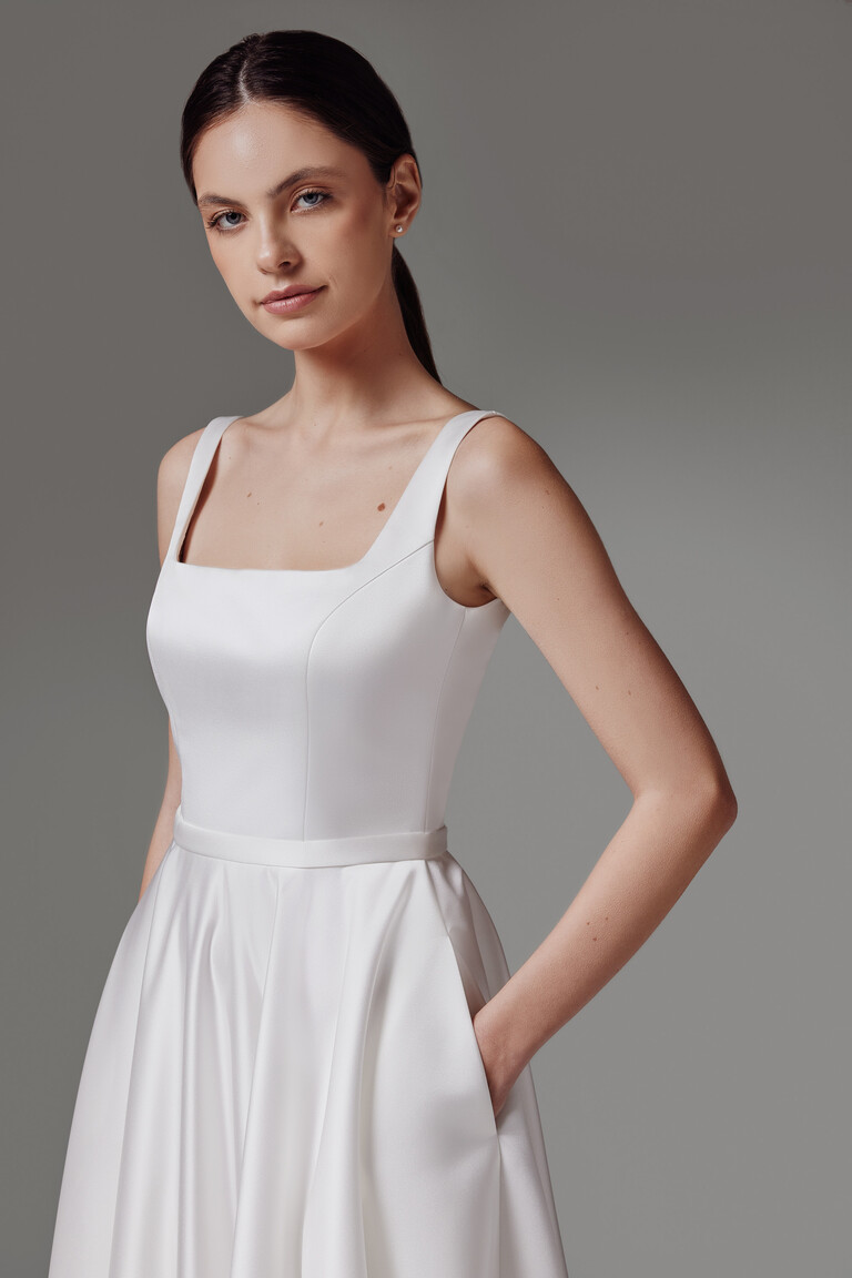Close up angled view of the Vlada off-white satin wedding dress bodice with a square neckline and pocket detail