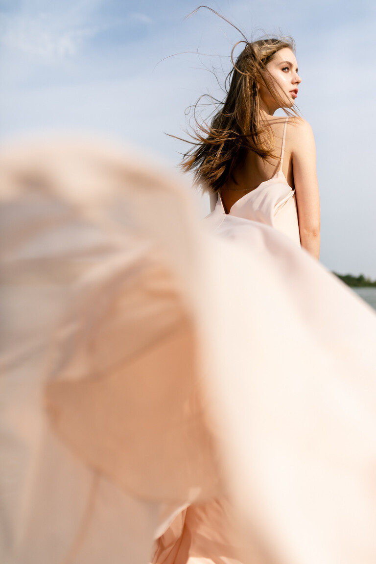 Motion shot of the Unona Isa peach dress from the back highlighting the voluminous chiffon skirt and low open back.