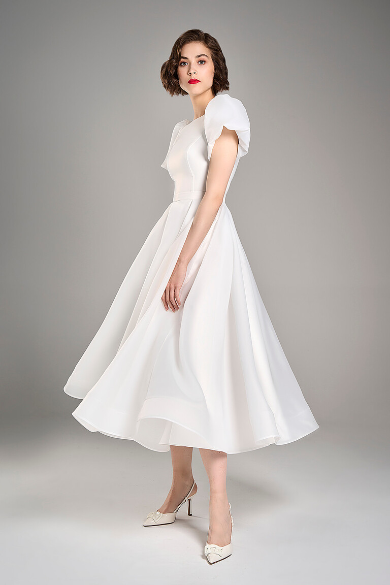Three-quarter view of Audrey midi ivory wedding dress showcasing flared organza skirt and fitted satin bodice