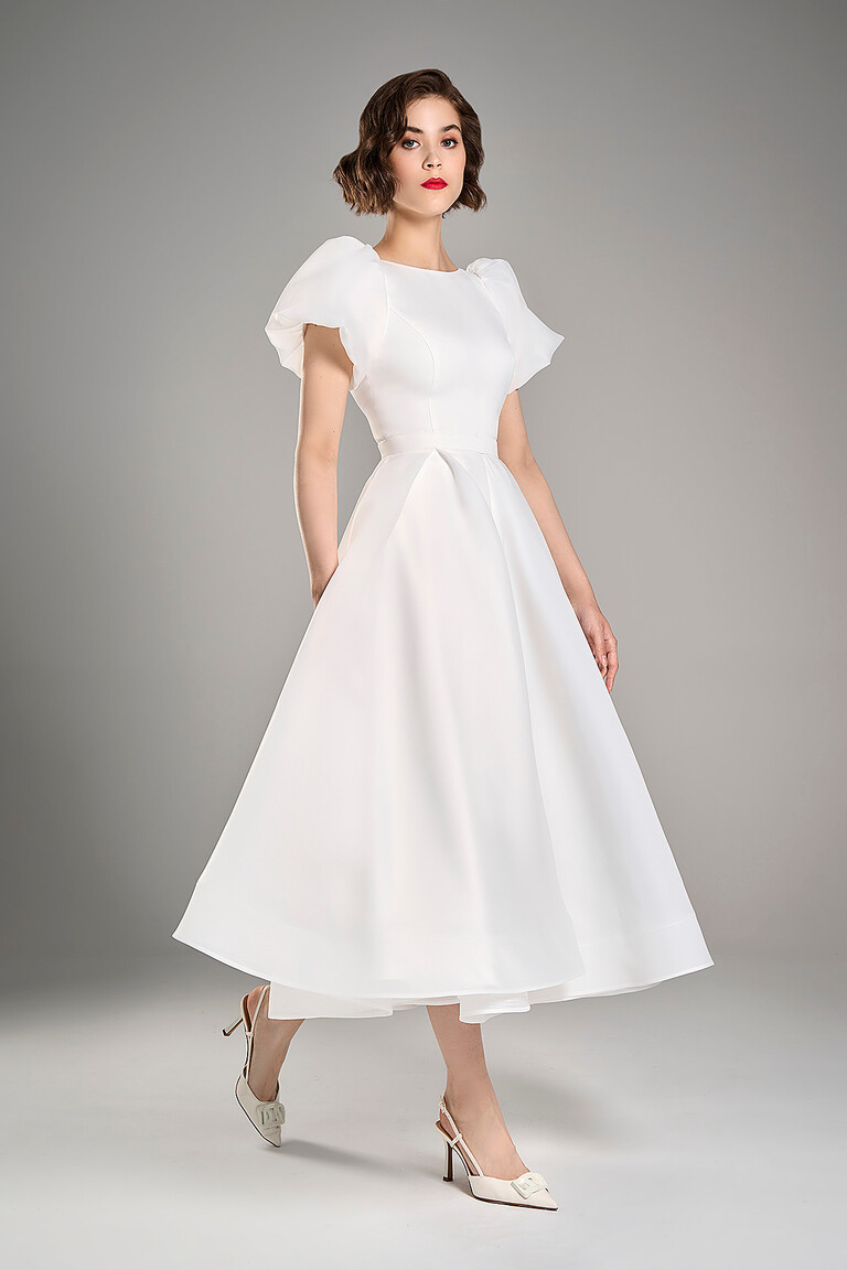 Full body view of Unona Audrey midi ivory bridal dress featuring organza puff sleeves and A-line skirt