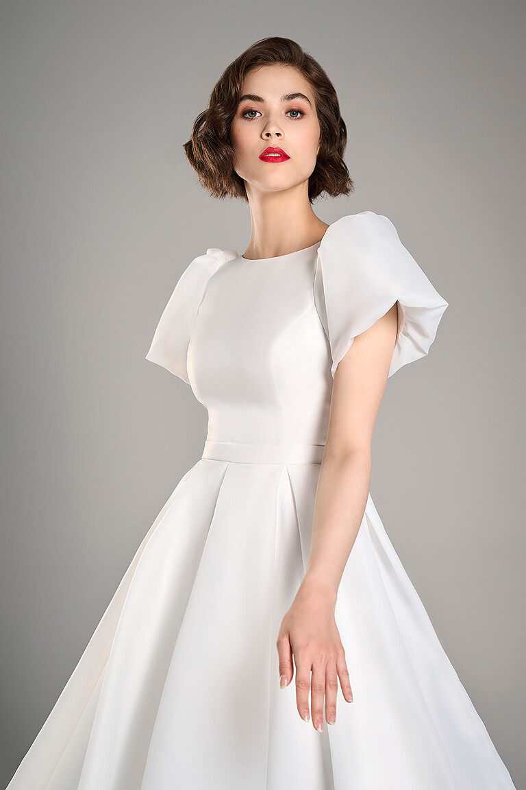 Angled front view of Audrey midi ivory wedding dress showing the defined waistline and flowing A-line skirt