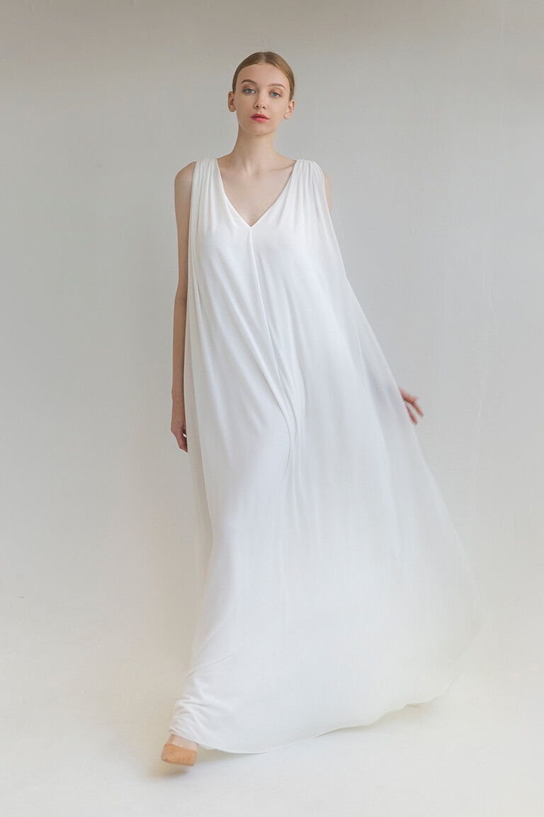 Model wearing the ivory Joan wedding dress by Unona, front view. Highlights the flowing A-line chiffon and central pleat detail.