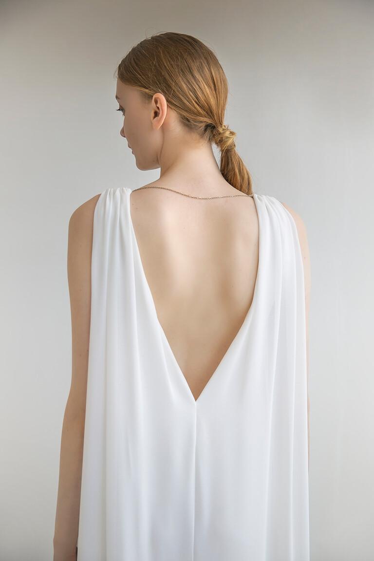 Back of the Unona Joan ivory wedding dress. The plunging V-back is accented by a thin chain on this sleeveless chiffon gown.