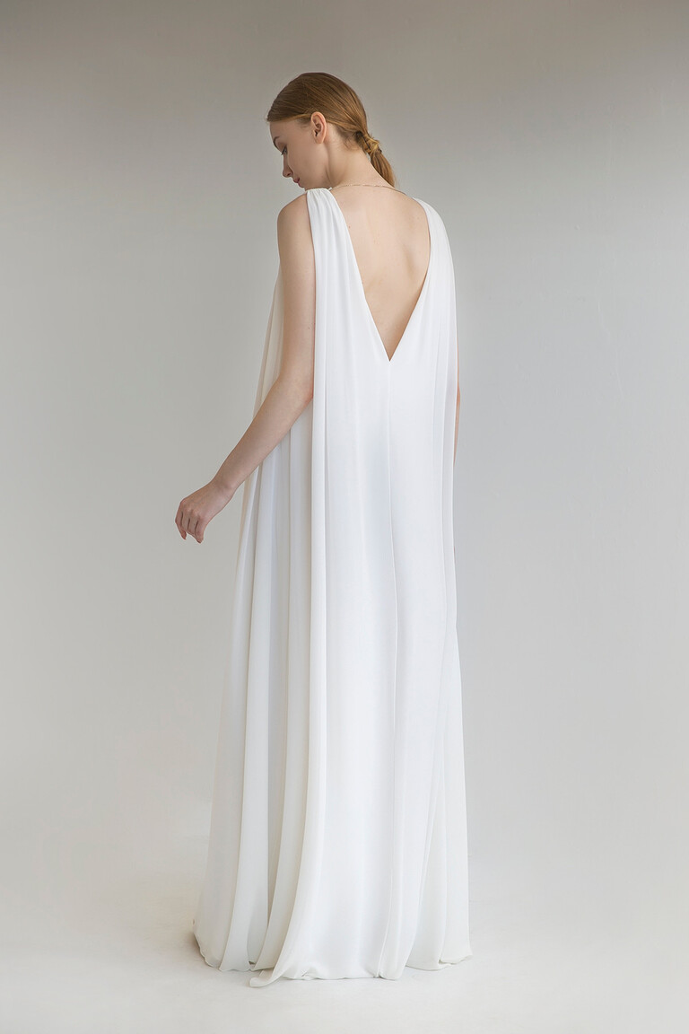 Full back view of the sleeveless Joan wedding dress by Unona. The ivory chiffon drapes beautifully from the deep V-back.
