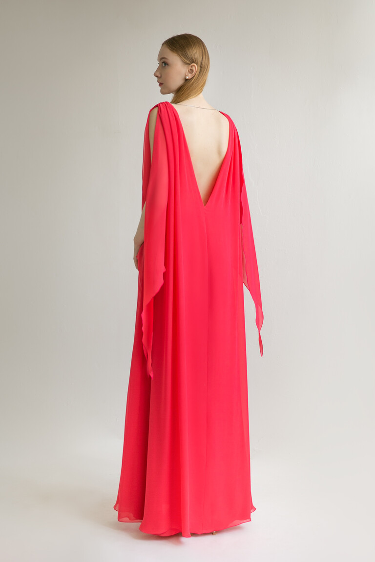 Back view of the Unona Joan red chiffon gown featuring a dramatic plunging V-open back and flowing cape sleeves.