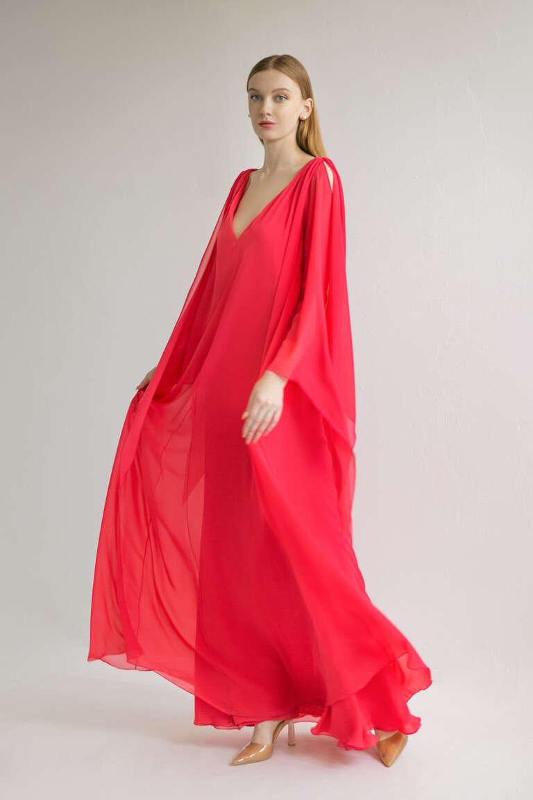 Unona Joan red evening dress from a front angle highlighting the unique cape sleeves with elegant shoulder cutouts.