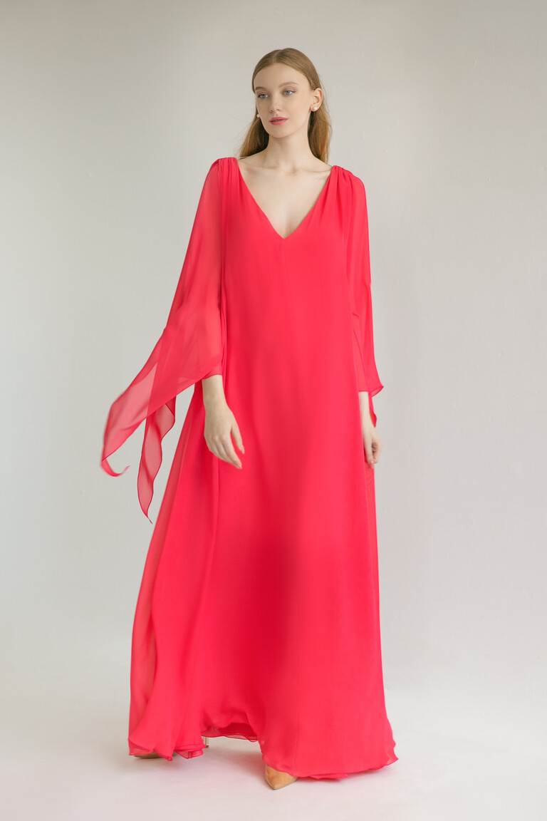 Model wearing the Unona Joan floor-length red dress with flowing semi-sheer chiffon sleeves and a deep V-neck.