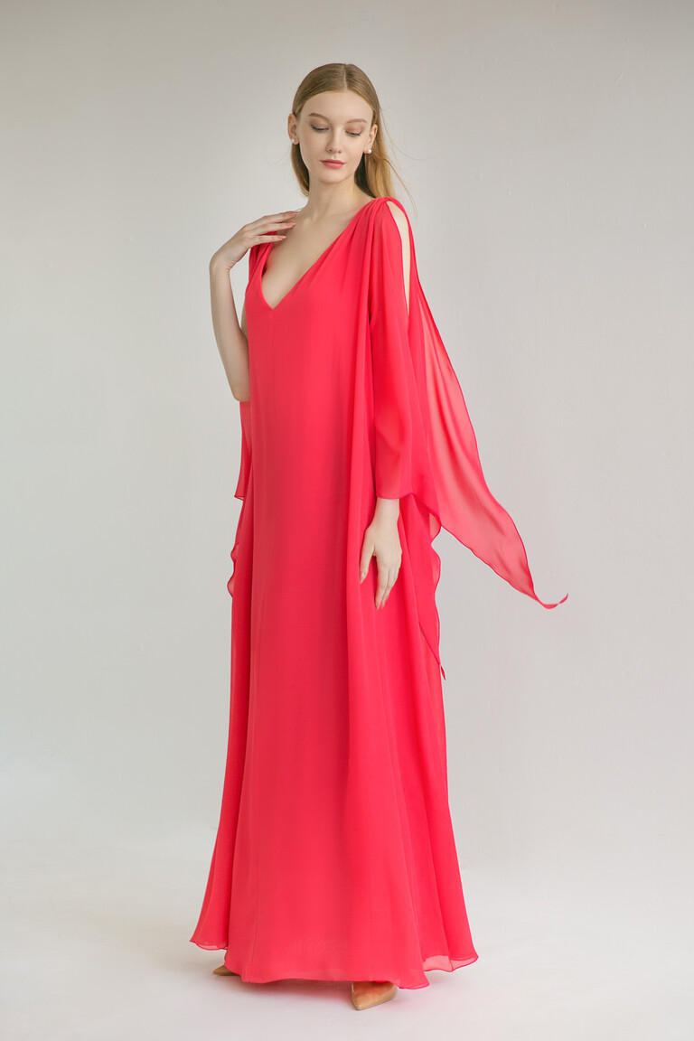 Three-quarter view of the Unona Joan red A-line gown showcasing its deep V-neckline and long cape-like flutter sleeves.