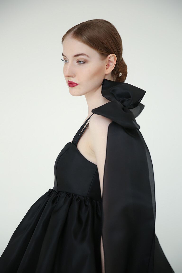 Side profile of Leoni black prom dress highlighting the voluminous organza balloon skirt and dramatic shoulder bow.