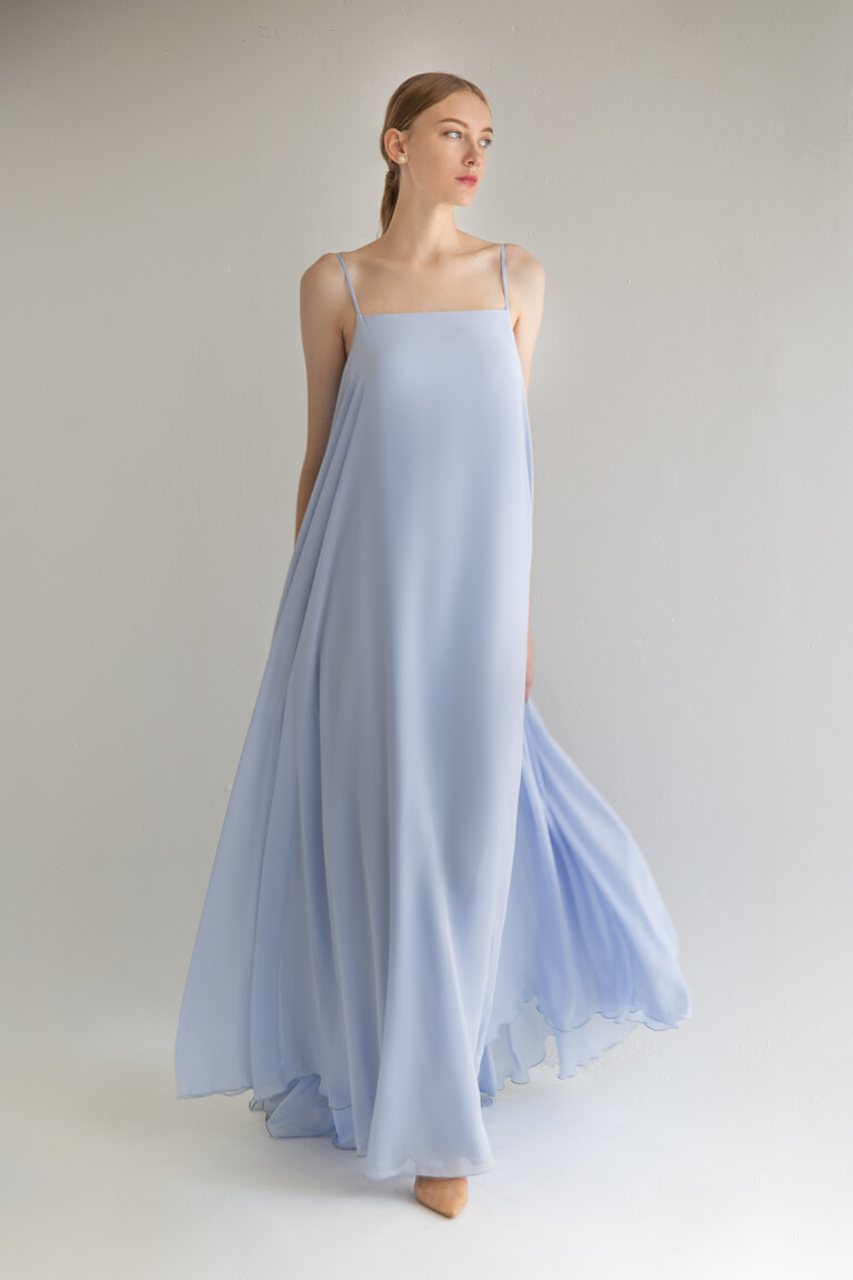 Three-quarter view of the Unona Isa blue occasion dress. A sleeveless floor-length chiffon gown with a flowing A-line cut.