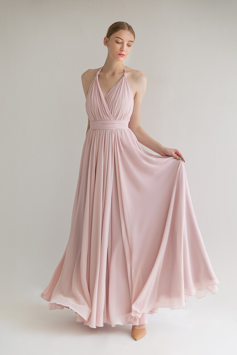 Model wearing the Unona Calypso powder pink A-line dress with a draped v-neck and soft flowing chiffon skirt