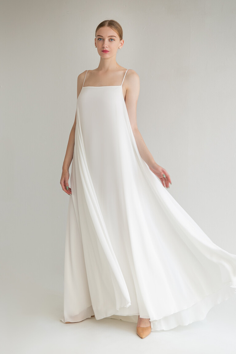 Full front view of the minimalist Unona Isa wedding dress in ivory. This sleeveless chiffon gown features a simple A-line trapeze shape.