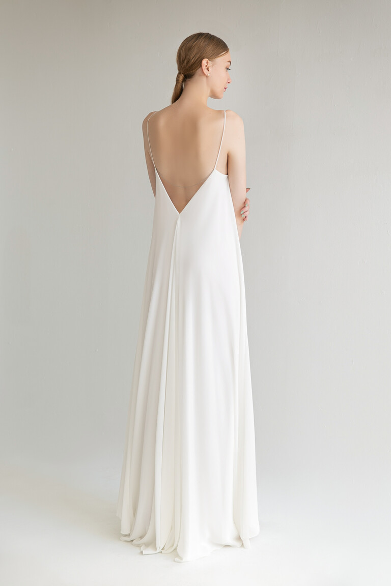 Full back view of the Unona Isa ivory chiffon wedding dress. Showcasing the deep V-shaped open back and floor-length skirt.