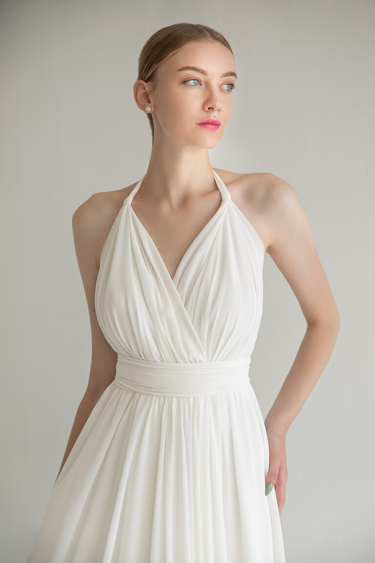 Unona Calypso ivory chiffon bridal gown shown from a three-quarter angle, detailing the draped V-neck and wide waistband.
