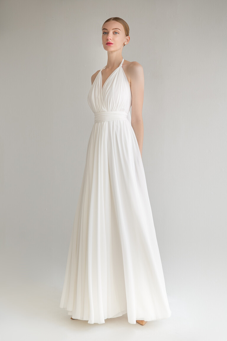Model wearing the sleeveless Calypso wedding dress by Unona in ivory, showcasing the draped V-neck halter bodice from the front.