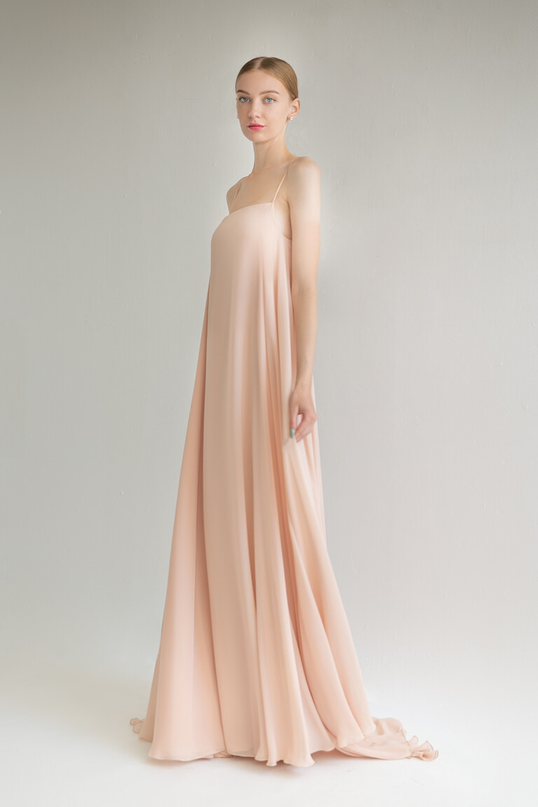 Three-quarter view of the Isa peach evening dress highlighting the flowing A-line chiffon skirt and slight train.