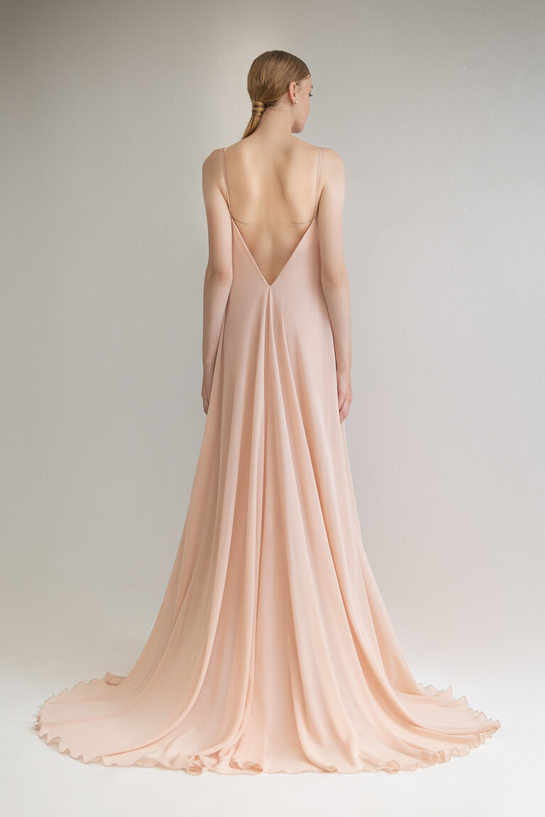 Full back view of the Isa floor-length peach dress showing the deep V-back and flowing chiffon train in a studio setting.