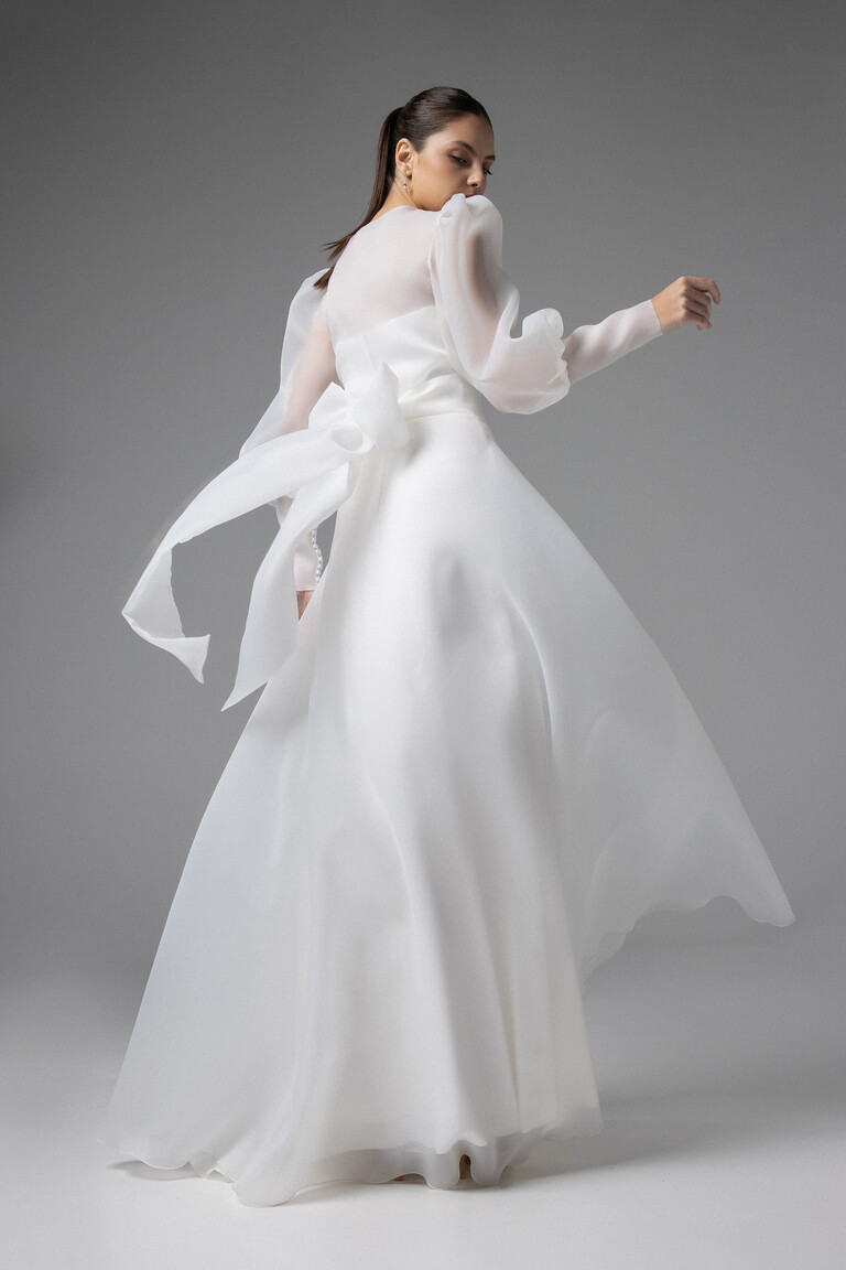 Back View of Cape Sonia Bridal Wrap Featuring Elegant Waist Bow Back view of Cape Sonia ivory organza bridal cape showing sheer back draped fabric and a large elegant waist bow.