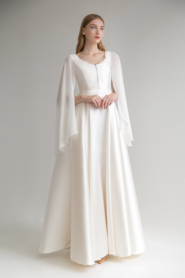 Full front view of Edite vintage satin wedding dress in ivory featuring scoop neck front zipper and long cape sleeves