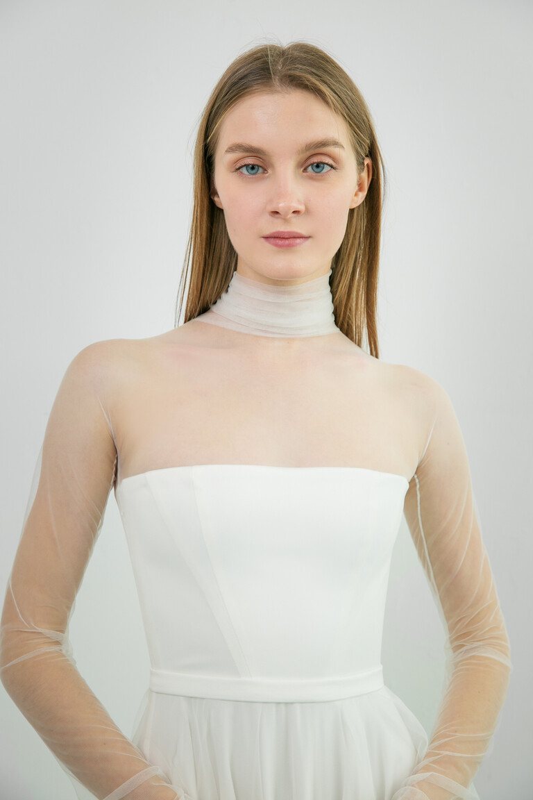 Modern Illusion Neckline Details on Liz Gown Front view of the Liz ivory bridal gown showcasing a modern minimalist satin bodice with sheer high neck and long sleeves.