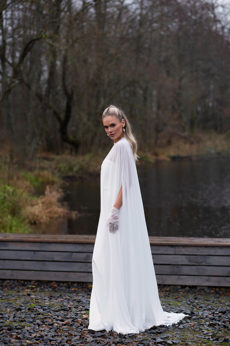 Draped Ivory Chiffon Wedding Cloak Veid Side View Side view of the floor-length ivory chiffon bridal cape Veid by Unona draping elegantly over a wedding gown