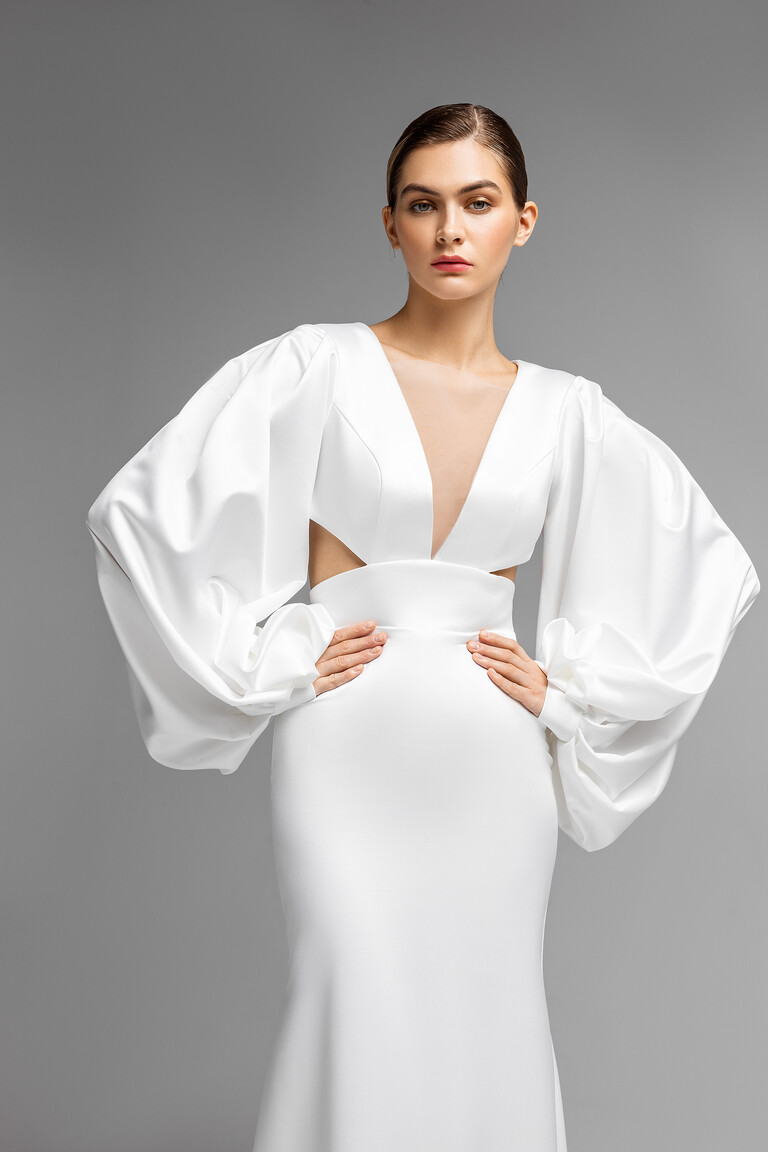 Glamorous Plunge Neckline and Puffed Sleeves Detail Close front view of Hannah ivory bridal gown featuring a deep plunge neckline, side cutouts, and glamorous puffed sleeves.