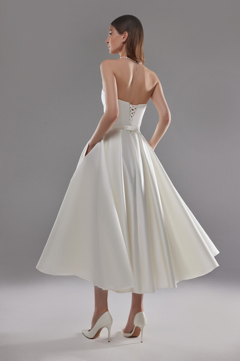 Back view of Lizzie ivory midi wedding dress featuring a lace-up corset back and side pockets.