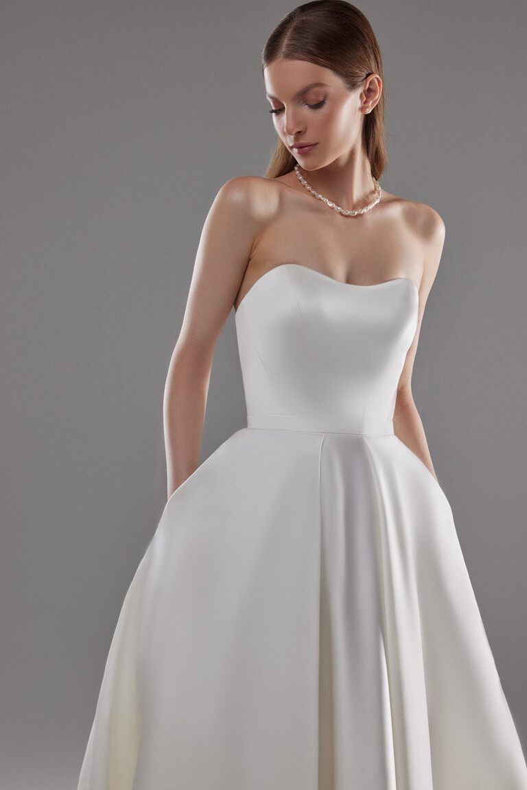 Close Up of Lizzie Sweetheart Neckline and Pockets Front view of Lizzie modern ivory strapless wedding dress highlighting the sweetheart neckline and functional pockets.