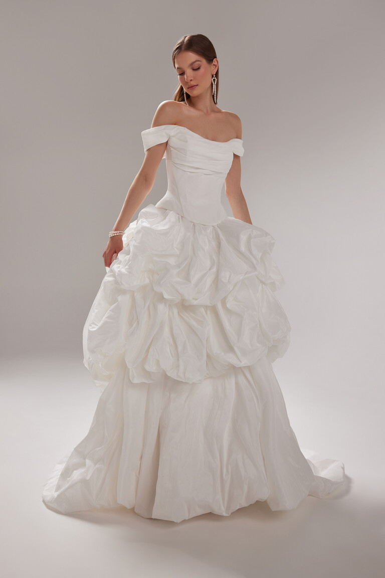 Unona Paradise Voluminous Ruffled Taffeta Off-Shoulder Wedding Dress Paradise romantic off-shoulder ball gown by Unona. Off-white taffeta draped corset bodice with voluminous ruffled skirt.