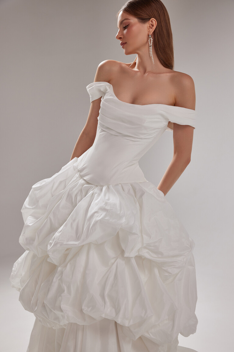 Paradise Voluminous Off-Shoulder Taffeta Wedding Dress Front Angle by Unona Front angle of Paradise off-white taffeta bridal gown. Off-shoulder draped bodice and voluminous ruffled skirt by Unona.