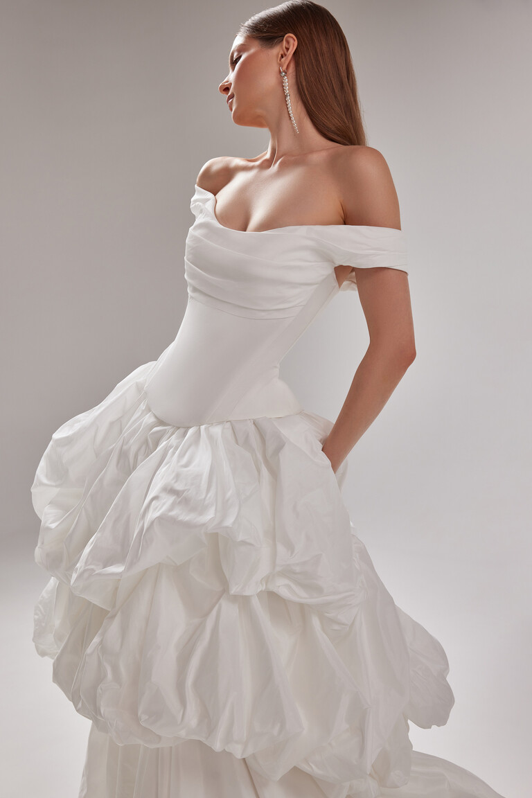 Paradise Off-White Taffeta Bridal Gown with Pockets and Ruffled Skirt Unona Paradise romantic wedding dress by Unona. Off-white taffeta off-shoulder gown with a drop waist ruffled skirt and pockets.