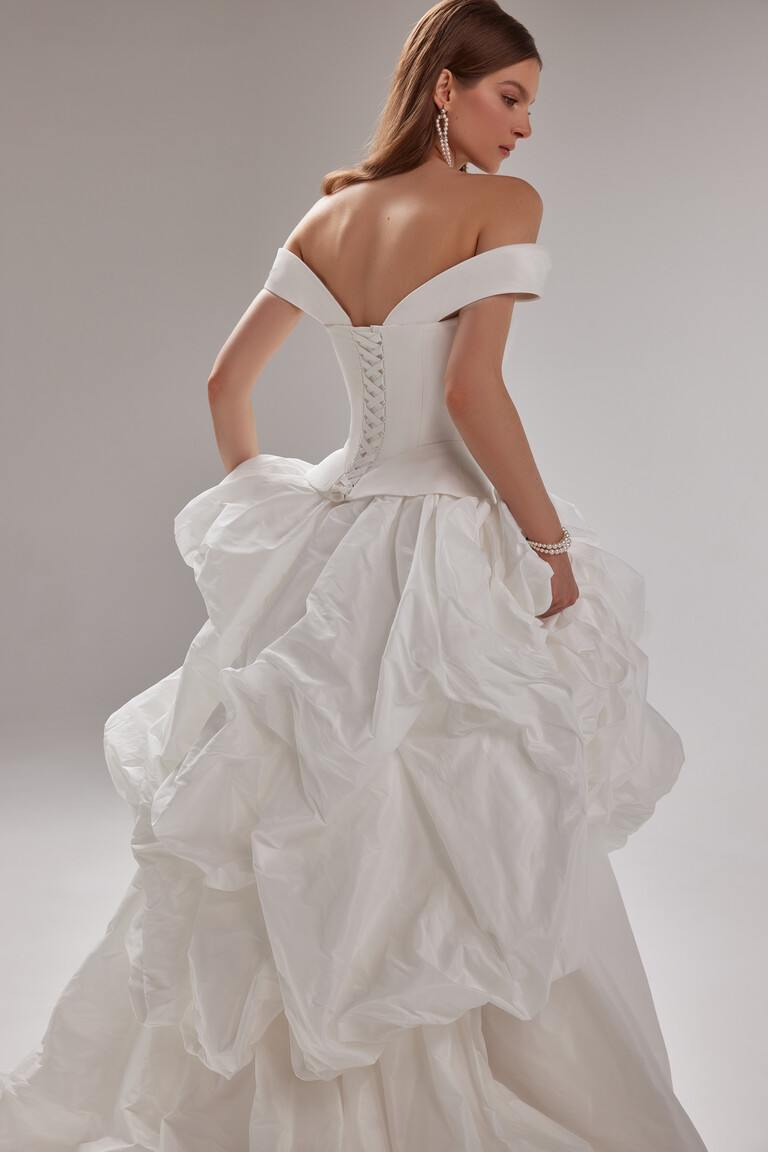 Paradise Taffeta Wedding Dress Lace-Up Back Details and Ruffled Drop Waist Back angle of Paradise wedding dress by Unona. Features off-shoulder straps, a lace-up corset back and ruffled drop waist.