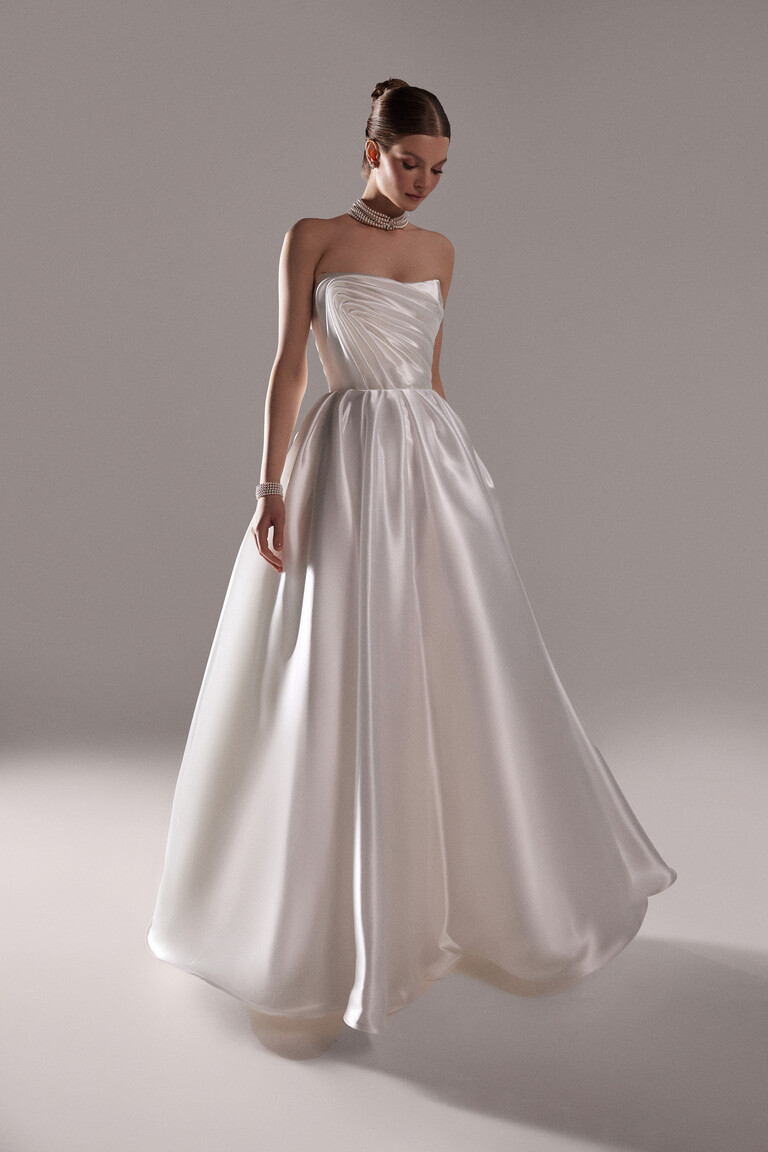 Elegant Nelly Strapless Ball Gown Front View Front view of Nelly off-white strapless ball gown wedding dress with asymmetrical draped bodice by Unona